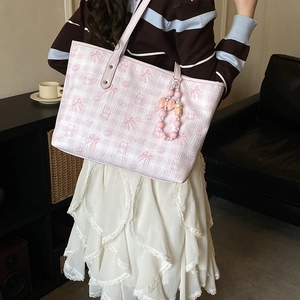 Detail of light pink tote bag featuring a checkered pattern, bow, and bear pendant charm
