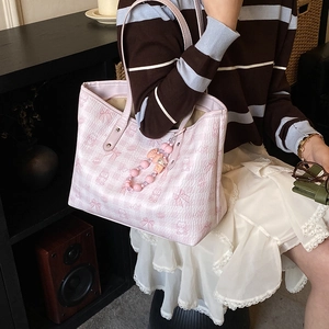 Detail of a pink tote bag with bear print and beaded charm in a warm room setting
