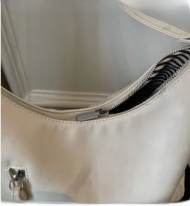 Close-up of silver metal zipper and striped lining on beige faux leather tote bag