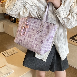 Detail of purple tote bag with cartoon bear prints and pink beaded bow charm