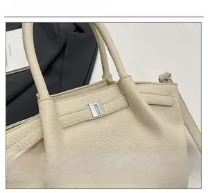 Gros plan de la boucle métallique en U argentée sur le sac à main en cuir beige crème