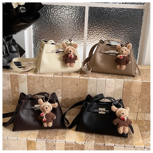 Detail view of four textured leather handbags with teddy bear charms on stone steps