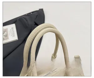 Détail des poignées arrondies et de la fermeture éclair sur sac en cuir grainé blanc crème