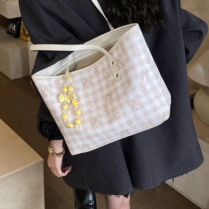 Close-up of beige plaid tote bag with cute bear pattern and yellow bead charm