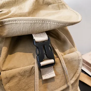Detail of durable black plastic side release buckle and strap on khaki nylon backpack