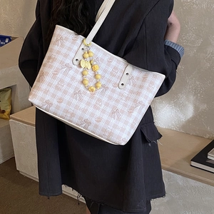 Detail of vintage beige grid tote bag with brown bear patterns and flower charm