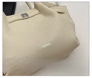 Détail de la texture cuir grainé crème avec boucle argentée et logo métallique