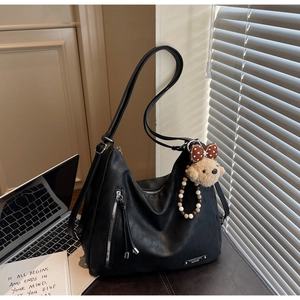 Detail of black large Hobo bag featuring a side zipper with leather tassel and teddy bear charm