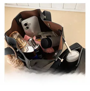 Interior view showing large capacity of black litchi pattern bucket bag with accessories