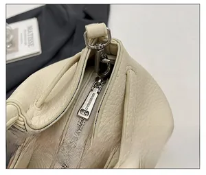 Détail de la fermeture éclair argentée et cuir grainé sur un sac à main crème chic