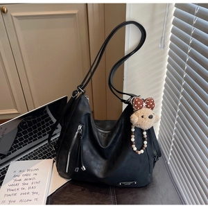 Detail of black matte leather hobo bag with teddy charm and front zipper pocket