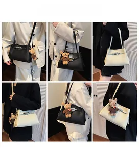 Detail view of the metal buckle closure and teddy bear charm on minimalist crossbody bag
