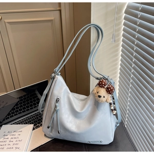 Detail of light blue vintage leather tote with cute bear pendant in office setting