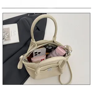 Détail montrant l'intérieur spacieux du sac seau beige avec téléphone et portefeuille