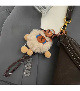 Detalle de colgante de peluche con cascabel y parche de cuero en el bolso cubo