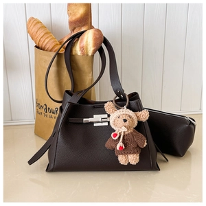 Detail of coffee brown pebble leather handbag with silver twist lock and bear charm