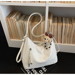 Detail of a beige PU leather hobo bag with adjustable strap and cute bear charm