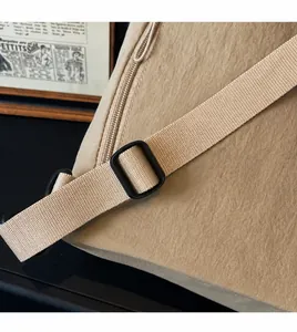 Detail of adjustable nylon strap and black plastic buckle on a beige travel backpack