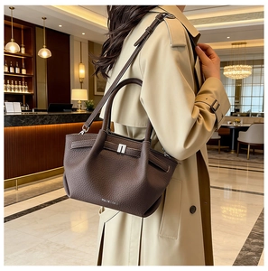Détail du sac à main en cuir marron foncé avec motif litchi, boucle argentée et bandoulière