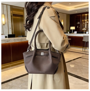 Détail d'un sac à main en cuir marron foncé avec bandoulière réglable et fermoir métallique