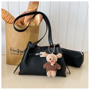 Close-up of black litchi grain leather bag with silver twist lock and cute bear charm