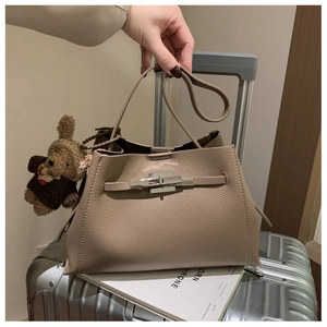 Detail of beige lychee leather handbag with silver twist lock and cute bear charm