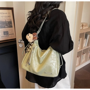 Detail view of avocado green hobo bag with side zipper and cute bear keychain charm