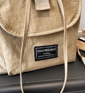 Close-up of khaki nylon backpack with crinkle texture and custom rectangular fabric label