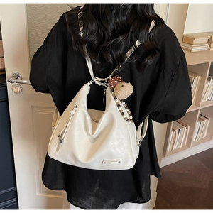 Detail of soft cream leather tote backpack with silver zipper and decorative tassels