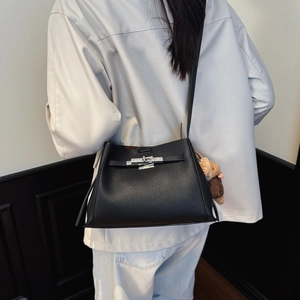 Detail of black pebbled leather crossbody bag with silver buckle and cute bear pendant