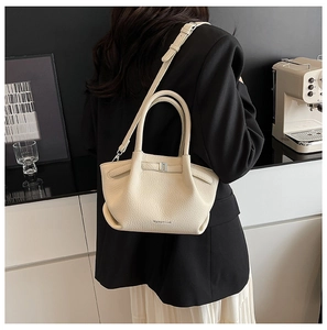 Détail de la texture en cuir grainé et du design plié du sac seau couleur crème