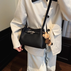 Detail of black pebbled leather crossbody bag with silver twist lock and knit bear charm