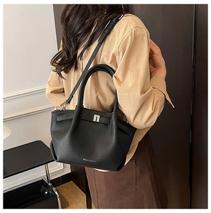 Détail du sac à main en cuir grainé noir montrant le fermoir en métal argenté et le grain