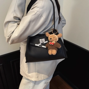 Detail of black pebbled leather handbag with silver twist lock and cute bear charm