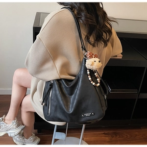 Detail of the large black hobo bag featuring metal zipper, bear charm and beaded pendant