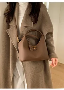 Nahaufnahme der warmbraunen Leder-Eimertasche mit goldenem Drehverschluss und Narbenleder