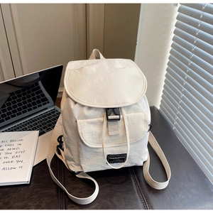 Detail view of cream canvas backpack featuring front pocket with black buckle closure