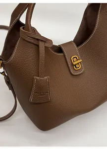 Detail der braunen Ledertasche mit weißer Kontrastnaht und goldenem Metallverschluss