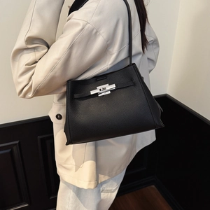 Close-up of black lychee pattern leather handbag with silver metal turn-lock closure