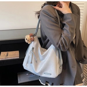 Detail of light blue leather hobo bag with side zipper and cute plush bear charm