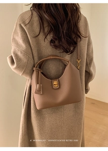 Detail einer braunen Eimer-Tasche aus Leder mit Lychee-Narbung und goldenem Drehverschluss