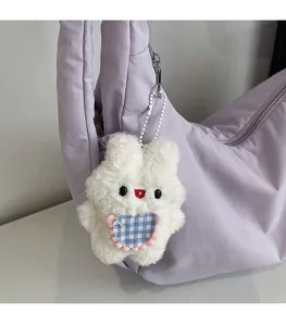 Detail of cute white plush bunny charm with blue checkered heart on a crossbody bag