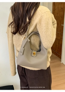 Detailansicht der grauen Leder-Eimertasche mit goldenem Verschluss an der Schulter