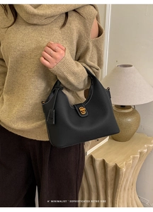 Detail der schwarzen Beuteltasche aus genarbtem Leder mit Goldschloss und Kontrastnähten