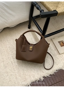 Detailaufnahme der dunkelbraunen Litschileder-Handtasche mit goldenem Drehverschluss-Detail