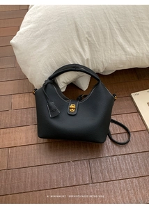 Nahaufnahme der schwarzen Ledertasche mit weißen Nähten und goldenem Verschluss