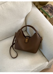 Makroansicht der dunkelbraunen Leder-Eimertasche mit goldener Schnalle auf dem Sofa