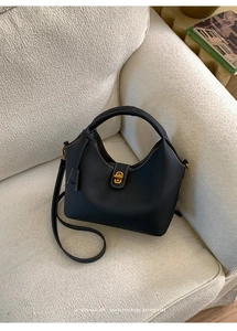 Detail der schwarzen Beuteltasche aus genarbtem Leder mit Kontrastnaht und Goldverschluss