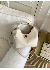 Detail der cremefarbenen Beuteltasche mit Leder in Litschi-Optik und goldener Schließe