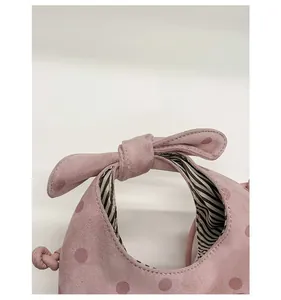 Détail de la poignée en nœud rose et du motif à pois sur le sac à main en daim
